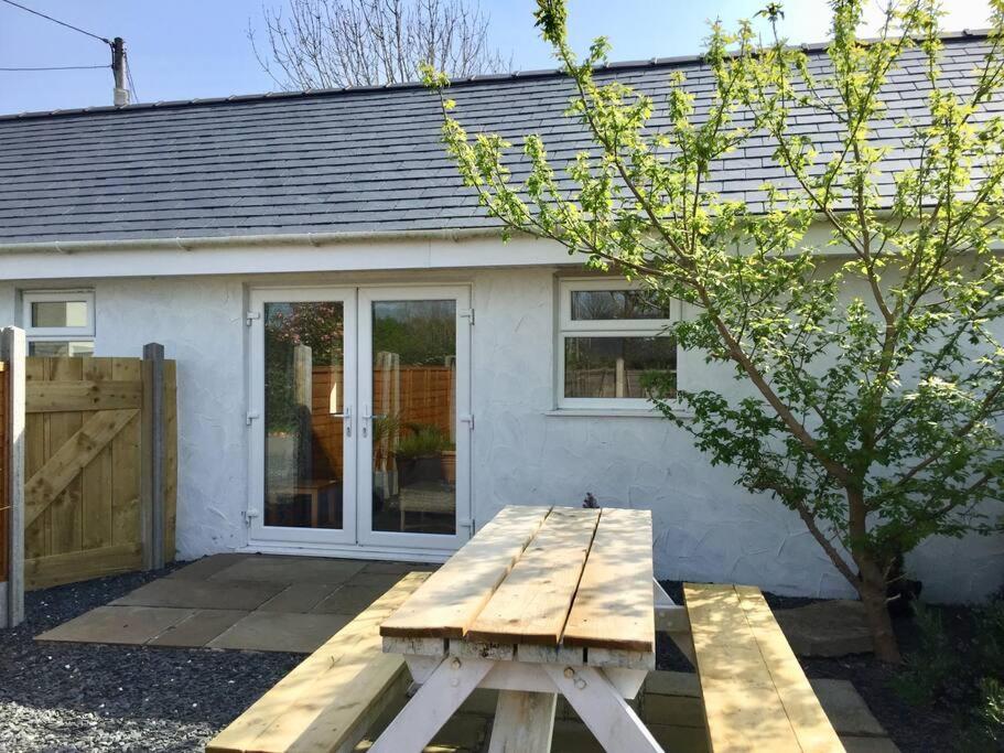 a wooden picnic table in front of a house at Orchard Cottage, Pwllheli, North Wales in Pwllheli