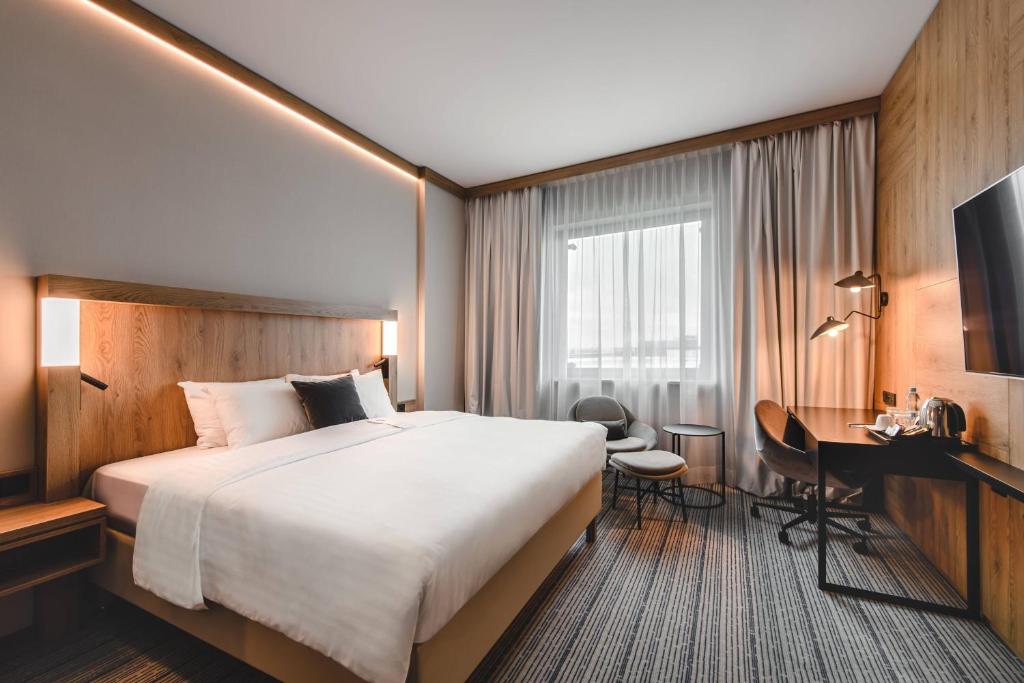a hotel room with a large bed and a desk at Courtyard by Marriott Warsaw Airport in Warsaw
