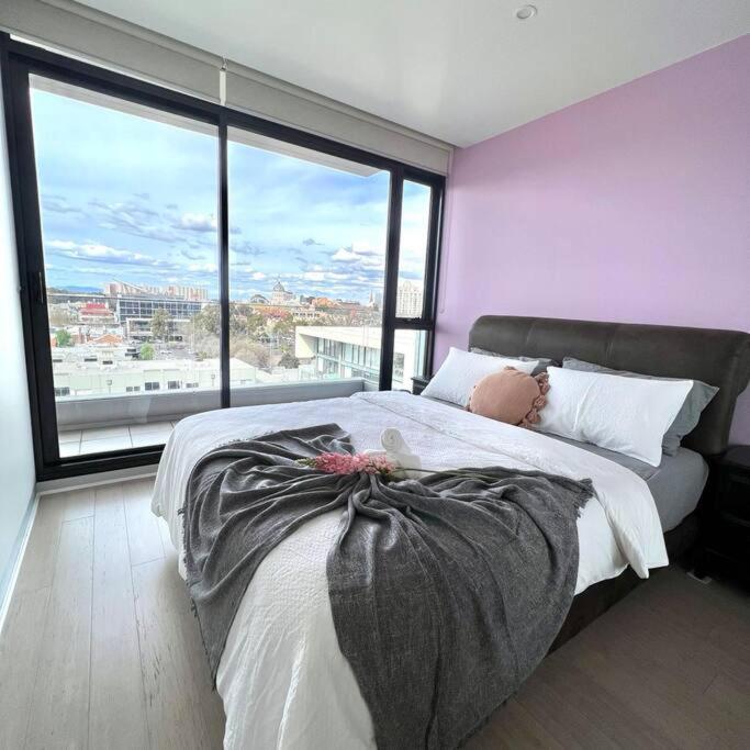 Carlton Stunning View Apartment with Free Parking -2 في ملبورن: غرفة نوم بسرير كبير مع نافذة كبيرة