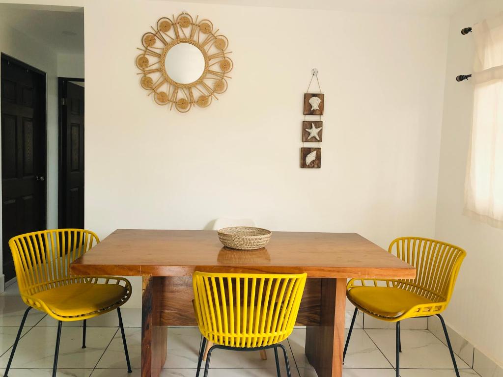 a dining room table with yellow chairs and a mirror at Casa Blanca Beachhouse - walking distance beach in Tamarindo