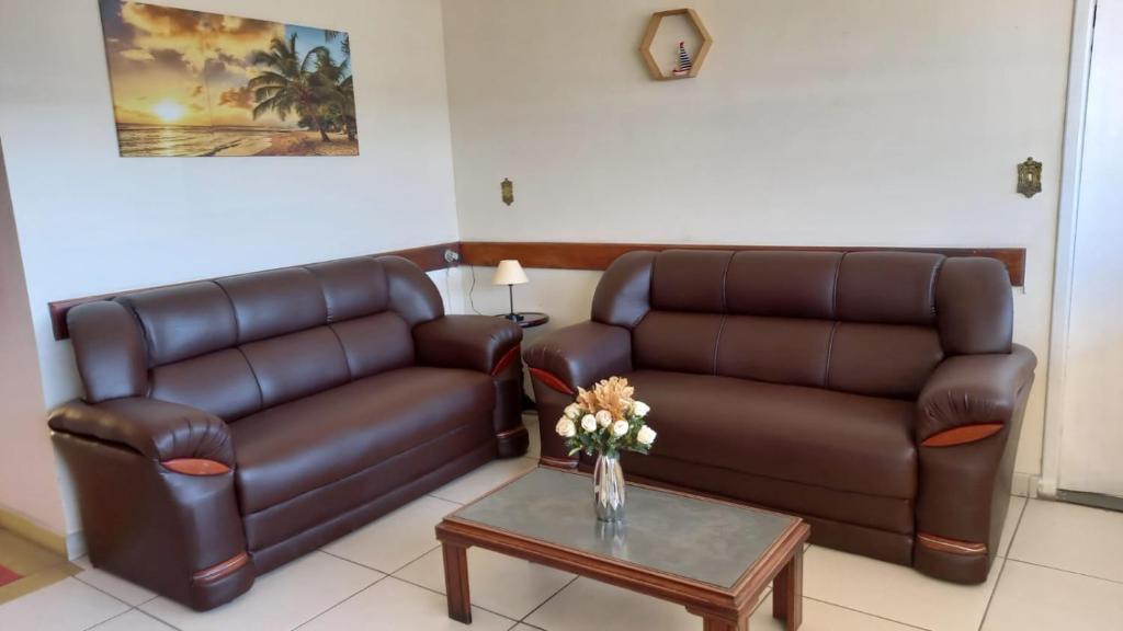 a living room with two leather couches and a table at HOTEL DOCE LAR in Campos dos Goytacazes