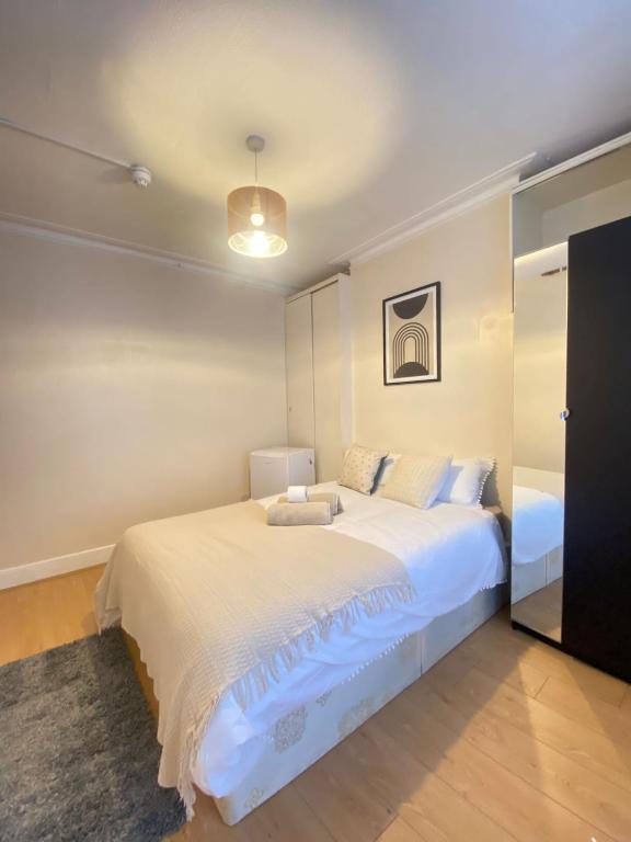 a bedroom with a large white bed and a mirror at Seven Sister's rooms in London