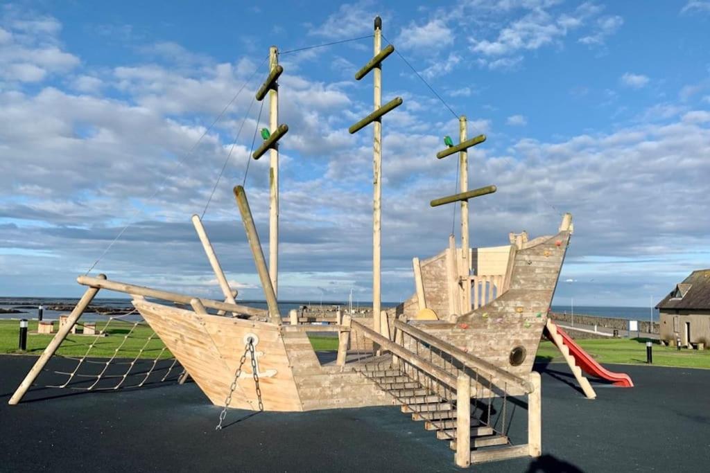 un parco giochi con una barca in legno con altalena di Ballywalter Beach House a Ballywalter