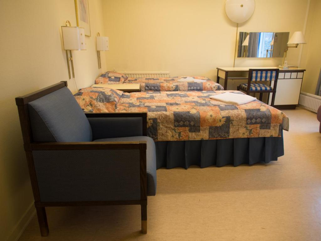 um quarto de hotel com duas camas e uma cadeira em Laitilan Kievari em Laitila