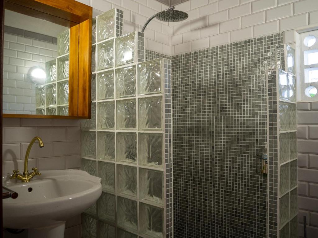 a bathroom with a sink and a glass shower at La petite Maison Bakov’ in Montjoly