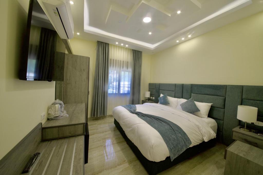 a bedroom with a large bed and a flat screen tv at Fragrant Rose in Wadi Musa