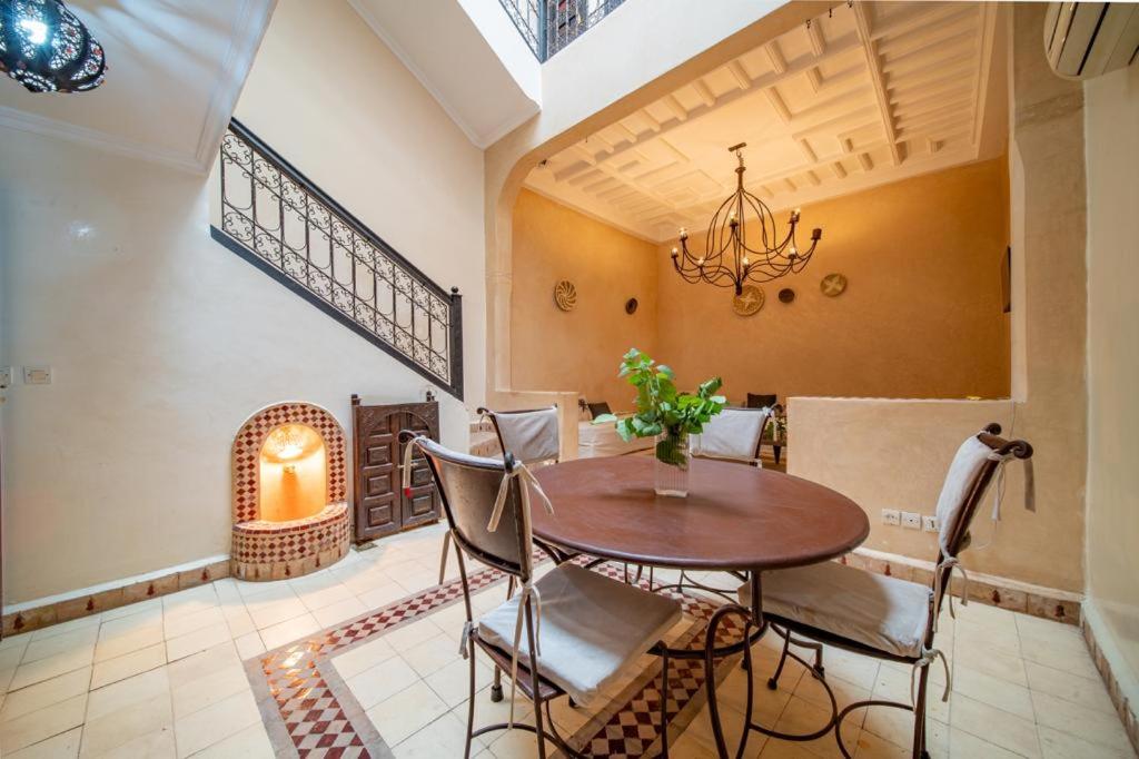 een eetkamer met een tafel, stoelen en een kroonluchter bij Riad Résidence Al Qaria Assiyahia Riad 22 in Marrakesh