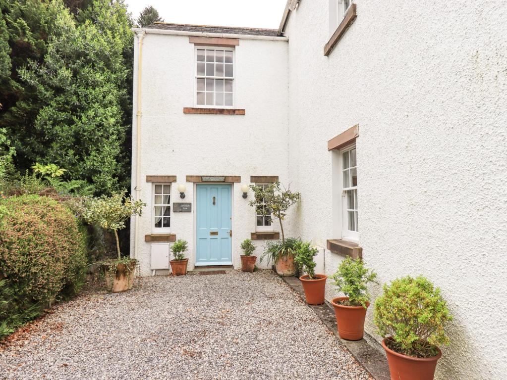 a white house with a blue door and potted plants at Grisedale View in Keswick
