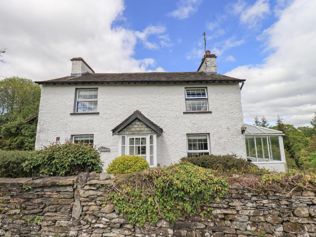 a white house on top of a stone wall at Greenstyles in Bowness-on-Windermere