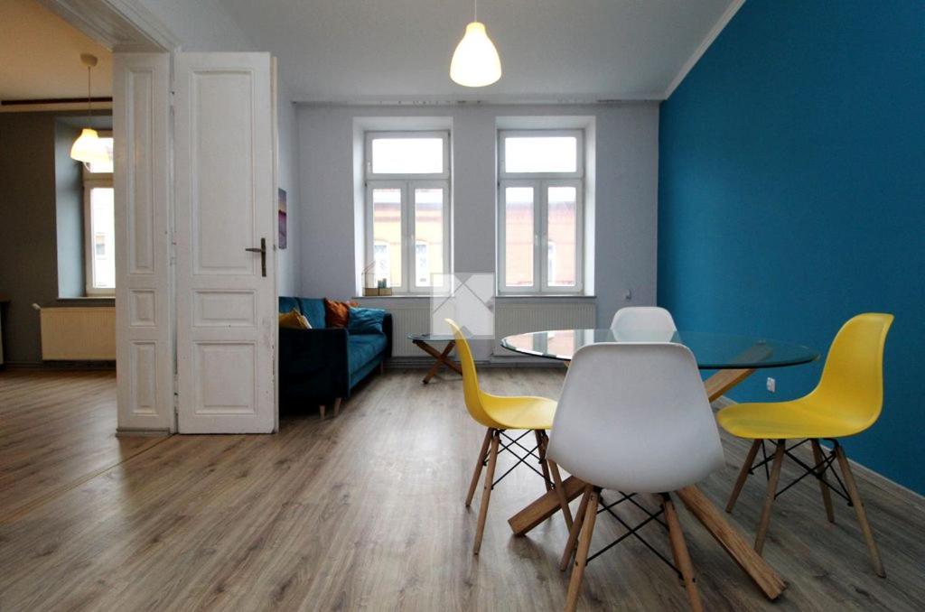 a living room with a table and yellow chairs at Blue Dollar Apartament in Przemyśl