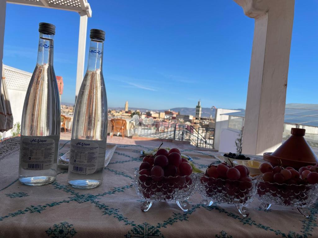 dos botellas de vino y tazones de fruta en una mesa en DAR ALKATIB MEKNES, en Meknès