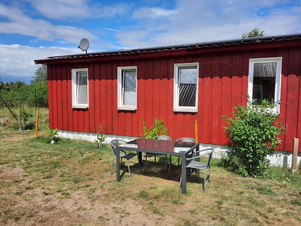 a red house with a table in front of it at Ferienhaus am Vilzsee, Mirow in Diemitz