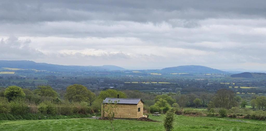 una pequeña casa de madera en una colina en un campo en Wye Valley Cabin, en Upper Welson