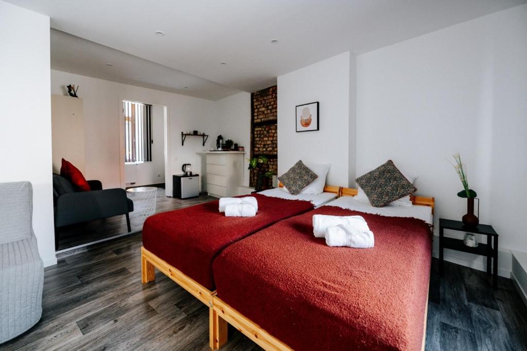een slaapkamer met een rood bed met witte handdoeken bij Logies by Suzan in Hasselt