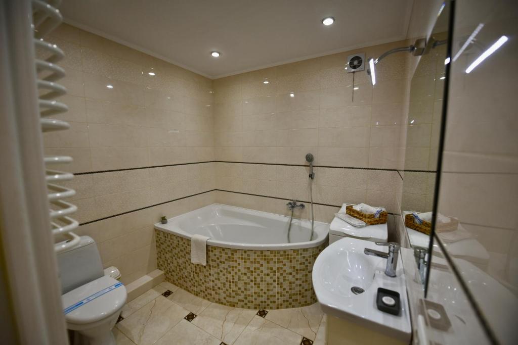 ein Badezimmer mit einer Badewanne, einem WC und einem Waschbecken in der Unterkunft Cozy apartment next to the park in Ternopil