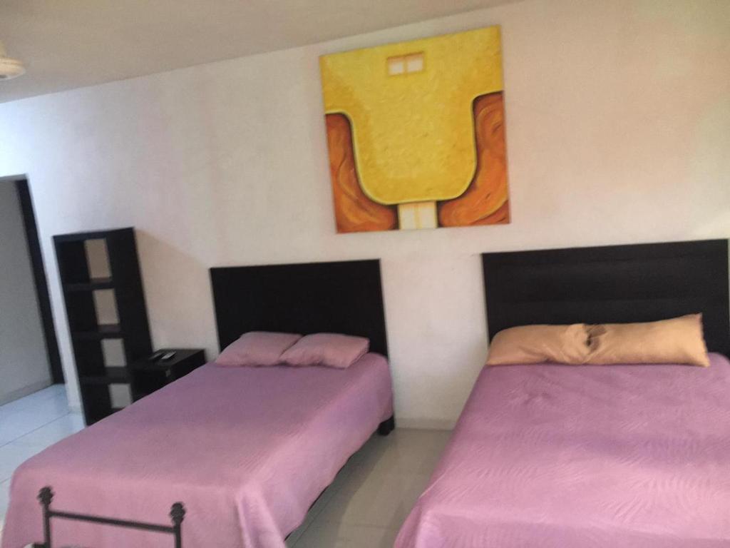 duas camas num quarto com um quadro na parede em Deptos Santa lucia em Mérida