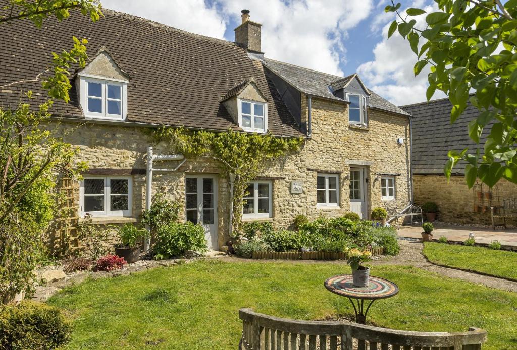 ein Steinhaus mit einem Tisch im Hof in der Unterkunft Mole End Cottage in North Cerney