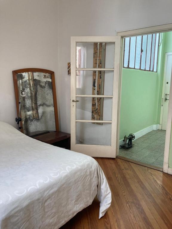 Schlafzimmer mit einem Bett, einem Spiegel und einer Tür in der Unterkunft Apartment Corazón de San Telmo in Buenos Aires