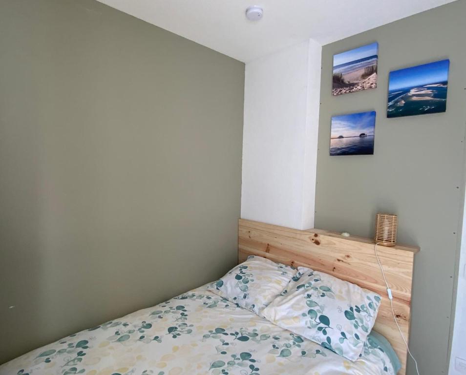 mała sypialnia z łóżkiem i obrazami na ścianie w obiekcie Chambre Studio au coeur du Bassin w mieście Biganos