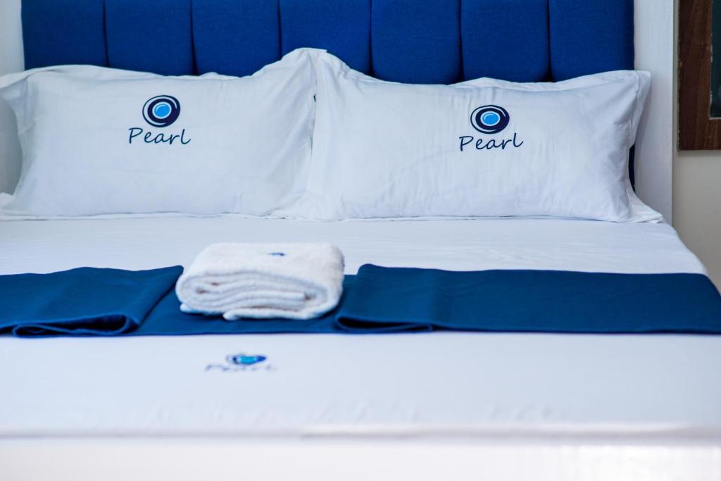 een wit bed met 2 kussens erop bij Pearl Suites and Hospitality in Bungoma