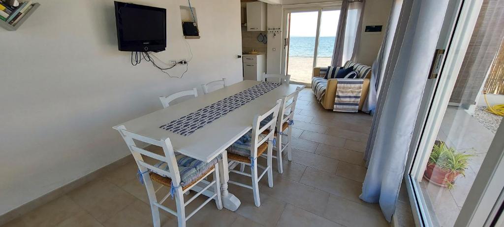 een tafel en stoelen in een kamer met uitzicht op de oceaan bij Casa da Gino in Calasetta