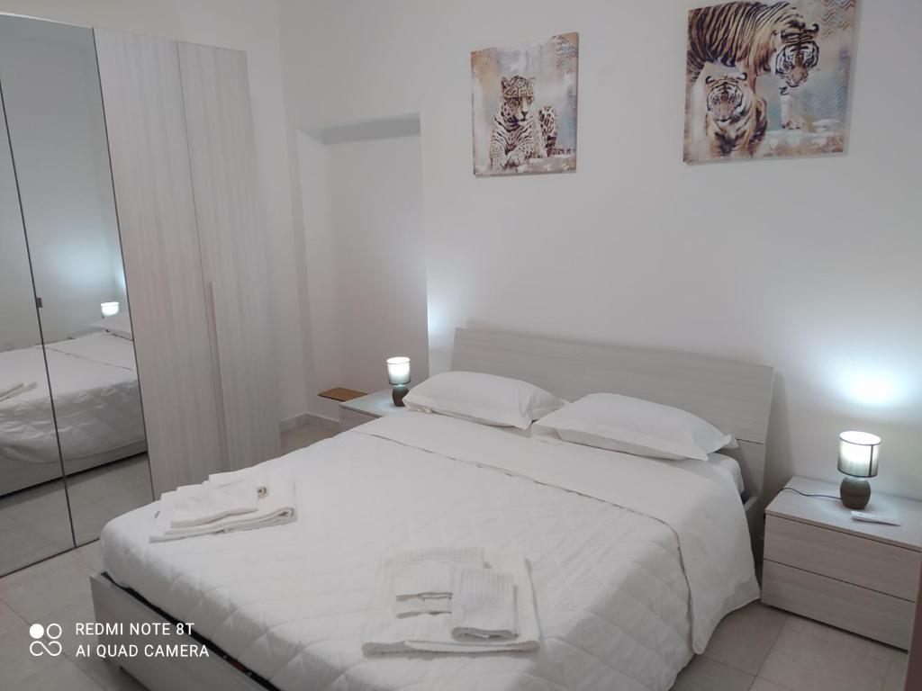 Dormitorio blanco con cama blanca y espejo en La casetta di Alessandro, en Matera