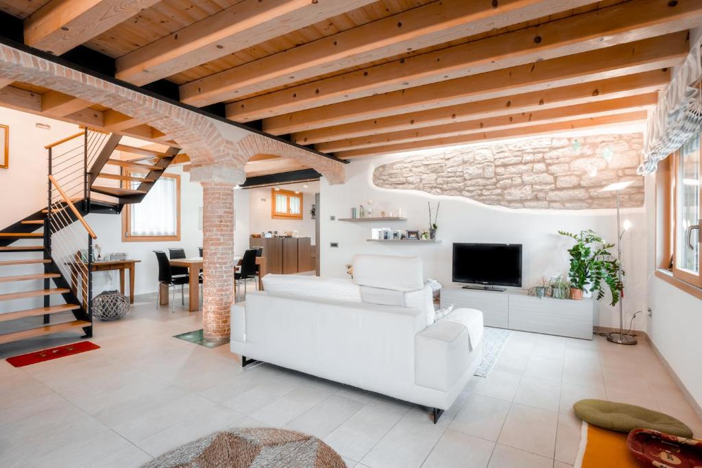 een woonkamer met een witte bank en een televisie bij Una Chicca in Valdobbiadene