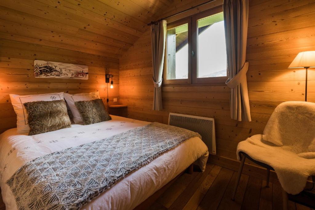 1 dormitorio con cama, ventana y silla en Le Mazot de Janton, en Combloux