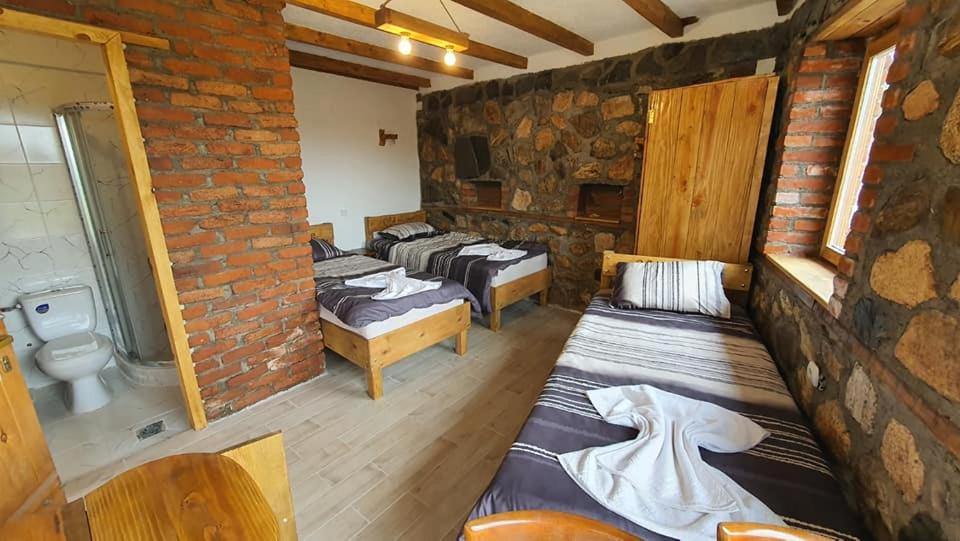 a room with four beds and a brick wall at Villa Old House BN in Bitola