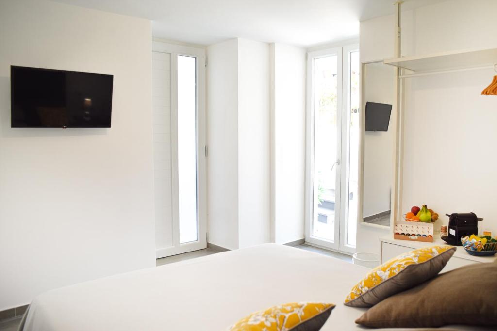 ein weißes Wohnzimmer mit einem TV und einem Sofa in der Unterkunft Variopinto Home in Ischia