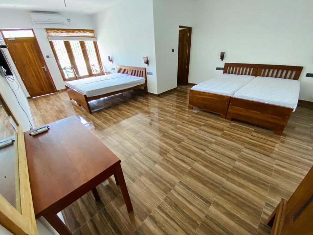 Zimmer mit 2 Betten und einem Tisch in der Unterkunft 贝鲁沃勒中国民宿 in Ambepitiya