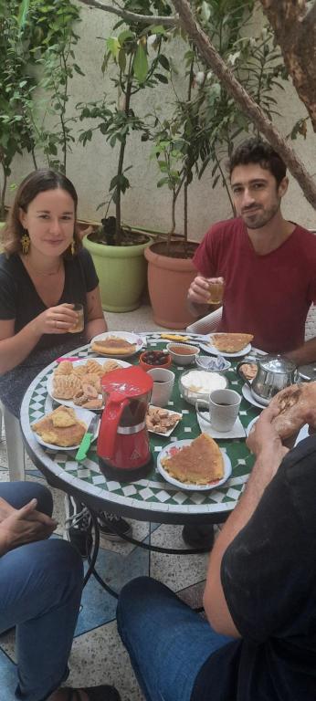 un grupo de personas sentadas alrededor de una mesa comiendo comida en Gite El Menzeh en Moulay Idriss Zerhoun