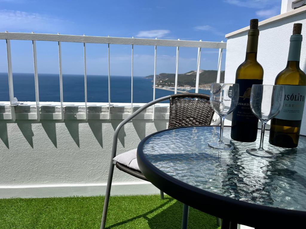 a table with two bottles and wine glasses on a balcony at Axenic Retreat - Panoramic Ocean View, Private Terrace, Sleeps 4, Ensuite Bathroom, New Redesign in Sesimbra
