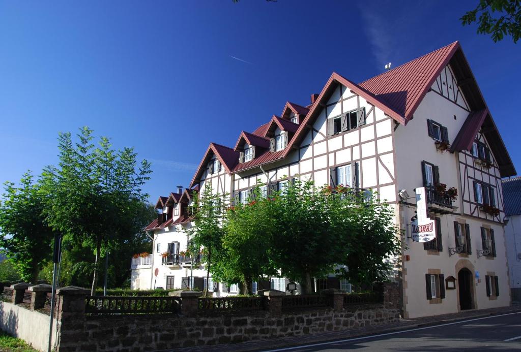 un grand bâtiment blanc avec un toit rouge dans l'établissement Hotel Rural Loizu, à Auritz