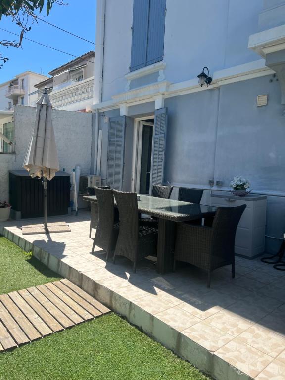 eine Terrasse mit einem Tisch, Stühlen und einem Sonnenschirm in der Unterkunft villa Siana in Antibes