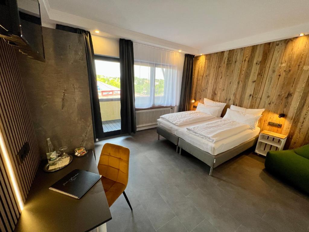 a bedroom with a bed and a desk with a laptop at JUNIPRO Hotel Schinderhannes in Weiskirchen