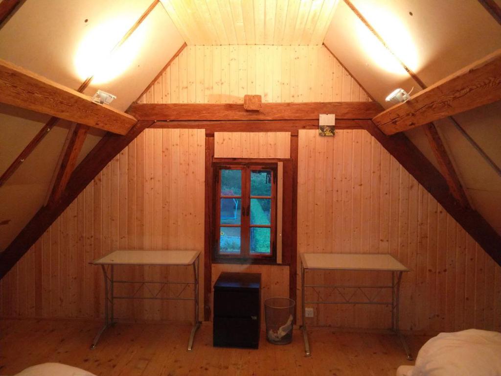 um quarto no sótão com duas mesas e uma janela em Dachstockzimmer in altem Stöckli em Steffisburg