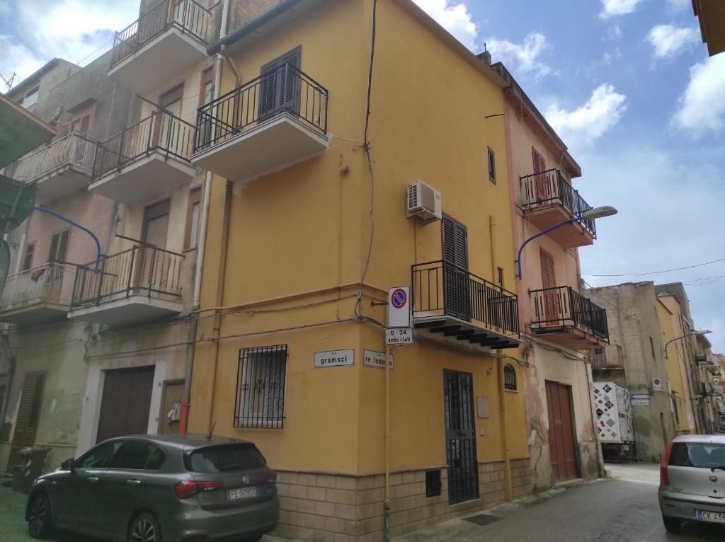 a yellow building with cars parked in front of it at Via Re Federico 13 in Ribera