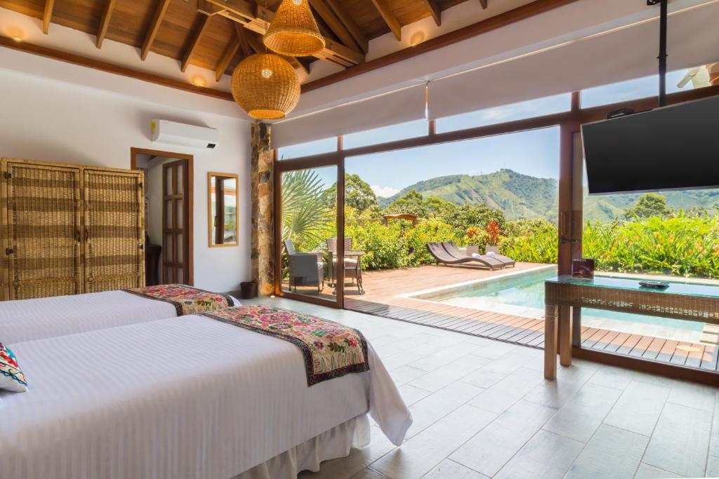 a bedroom with two beds and a pool at Hotel Spa La Colina in Pereira