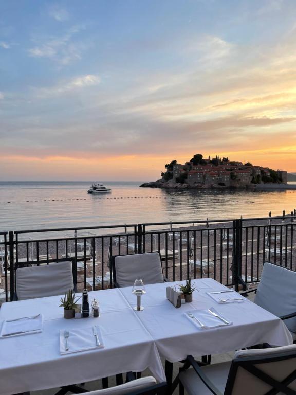 a table with chairs and a view of the ocean at Hotel California by Aycon in Sveti Stefan