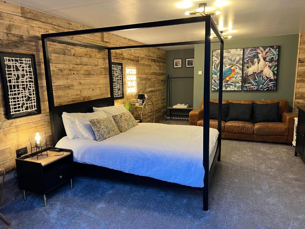ein Schlafzimmer mit einem Himmelbett und einem Sofa in der Unterkunft Boutique Shrewsbury Suites in Shrewsbury