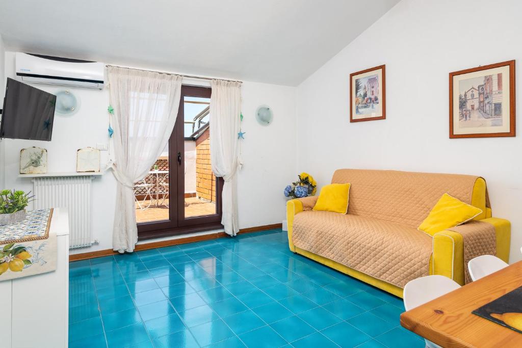 ein Wohnzimmer mit Sofa und blauem Boden in der Unterkunft La Mansardina dell'Agrumeto in Vico Equense