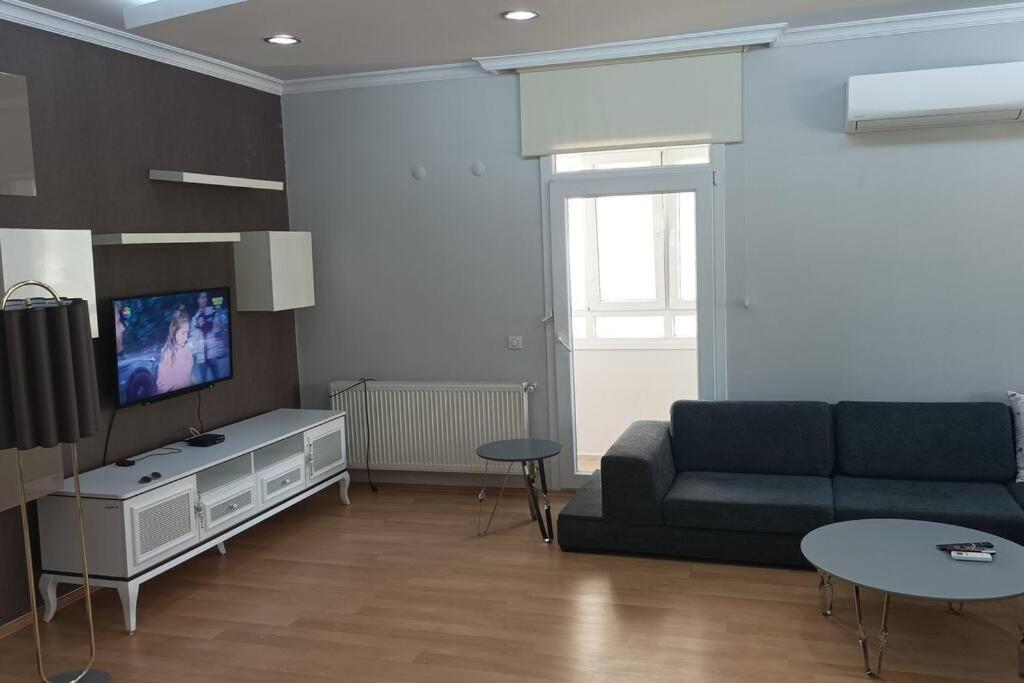 uma sala de estar com um sofá e uma televisão em Comfortable big house with 3 bedrooms and big living room em Burunabat