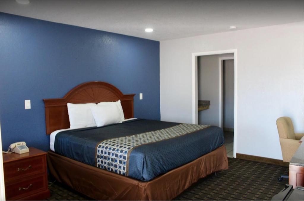 Economy Inn في Ada: غرفة نوم بسرير كبير بجدار ازرق