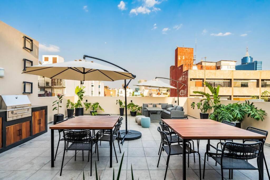 un patio con 2 mesas, sillas y una sombrilla en ¡Nuevo, cómodo y amenidades de lujo! Hospedaje para 10 personas., en Ciudad de México