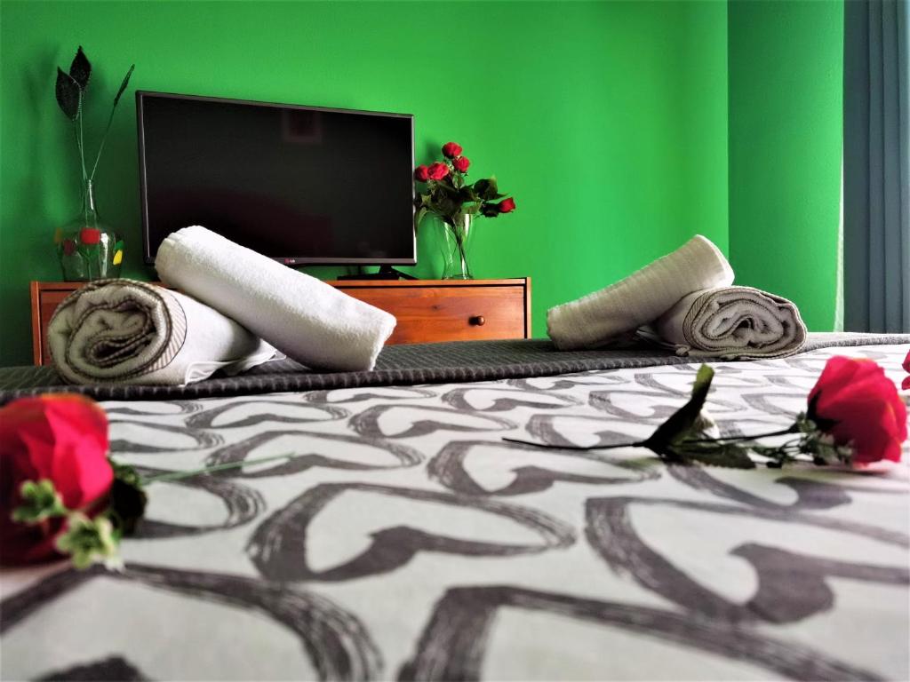 Un dormitorio con una pared verde y una cama con rosas. en Piso amplio y luminoso, La Pomar, en Langreo