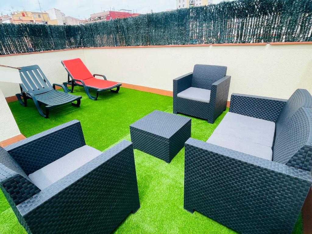 a patio with chairs and chairs on the grass at Beach Apartment Artigas in Badalona