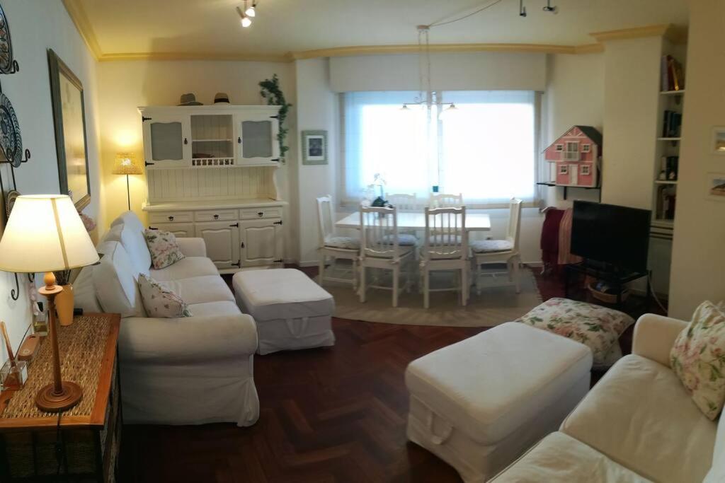 ein Wohnzimmer mit weißen Möbeln und ein Esszimmer in der Unterkunft Acogedor apartamento a pie de playa in Nigrán