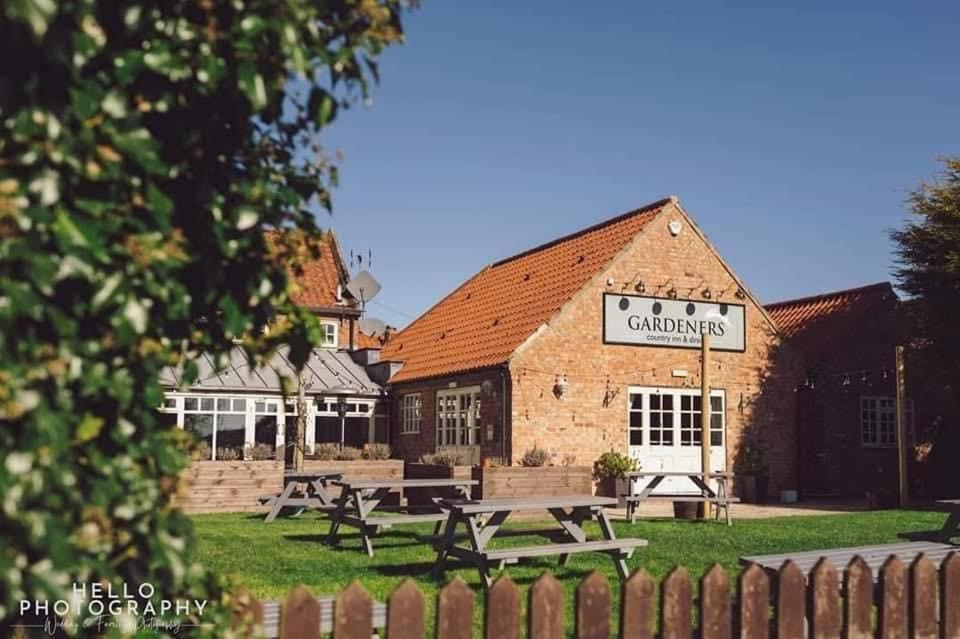 ein Gebäude mit Picknicktischen davor in der Unterkunft The Gardeners Country Inn in Goxhill