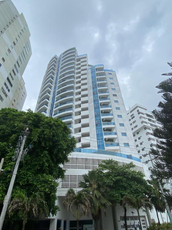 a tall building with palm trees in front of it at Apartamento lujoso a un minuto de la playa del laguito, la mejor playa de Cartagena de Indias in Cartagena de Indias